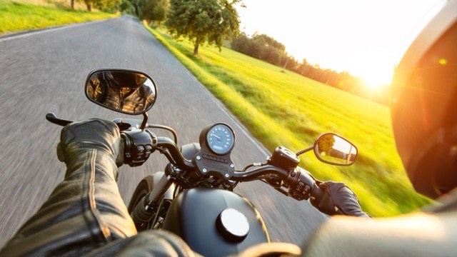 A lone rider chatting to a group at a roadside café, helmets scattered across the table